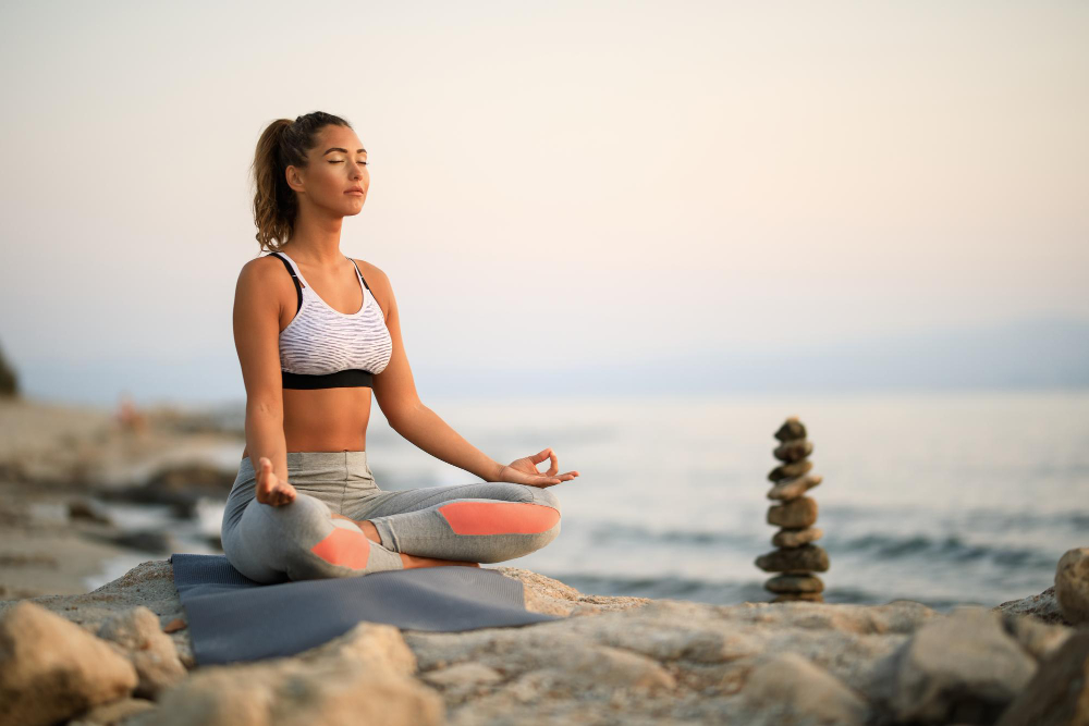 young-woman-practicing-yoga-relaxation-exercises-meditating-rock-beach-copy-space